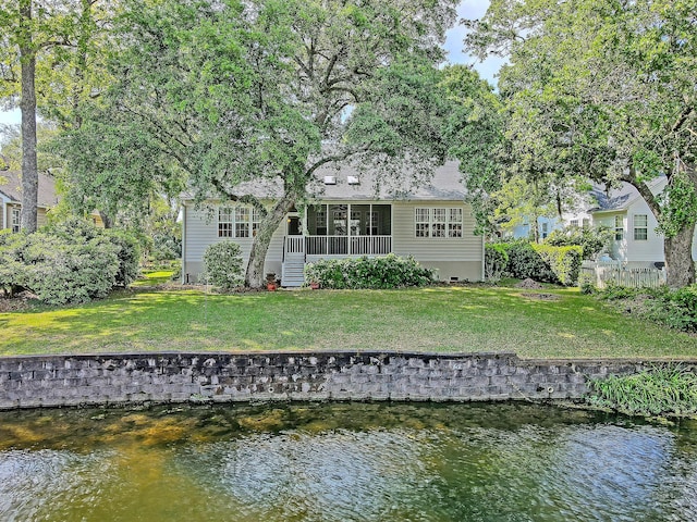 rear view of property with a lawn, fence, and a water view