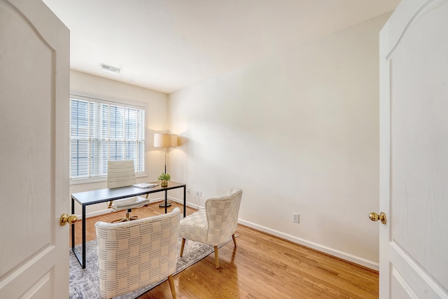 office space with baseboards, visible vents, and light wood finished floors
