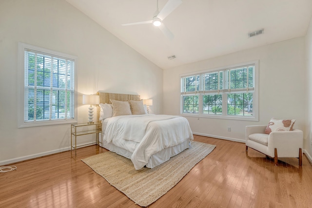 bedroom with visible vents, light wood-style flooring, a ceiling fan, baseboards, and vaulted ceiling