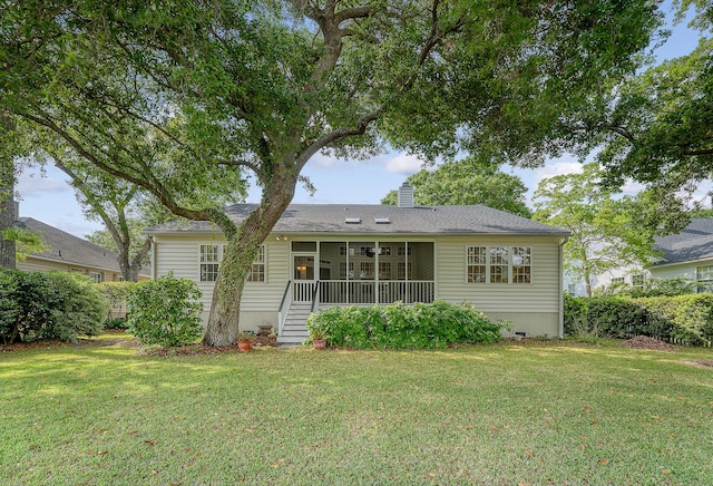 back of property featuring a lawn, a chimney, and a sunroom