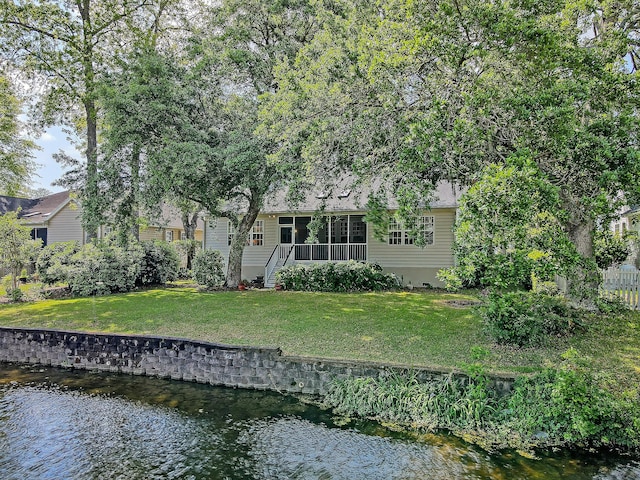 back of house with a water view and a yard