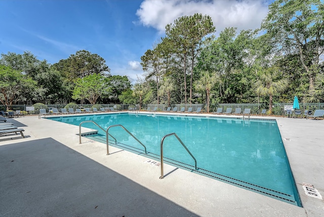 community pool with a patio area and fence
