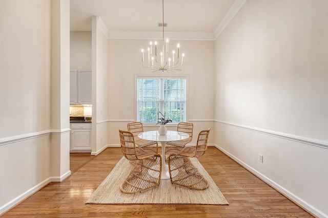 dining space with light wood-style floors, baseboards, ornamental molding, and a chandelier