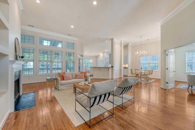 living room featuring baseboards, a chandelier, light wood finished floors, and a fireplace