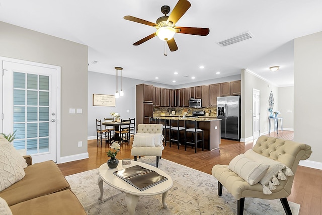 living room with a ceiling fan, wood finished floors, visible vents, baseboards, and recessed lighting