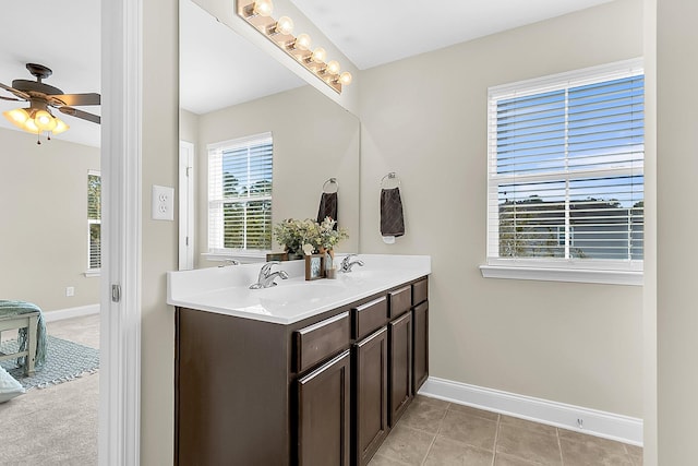 bathroom with a sink, baseboards, a ceiling fan, and double vanity