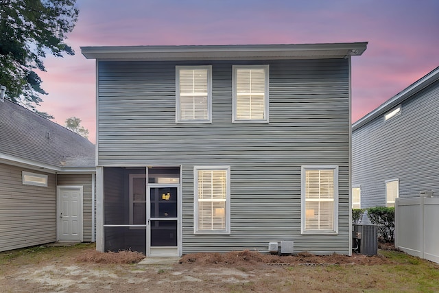 back of property with central AC unit, a sunroom, and fence