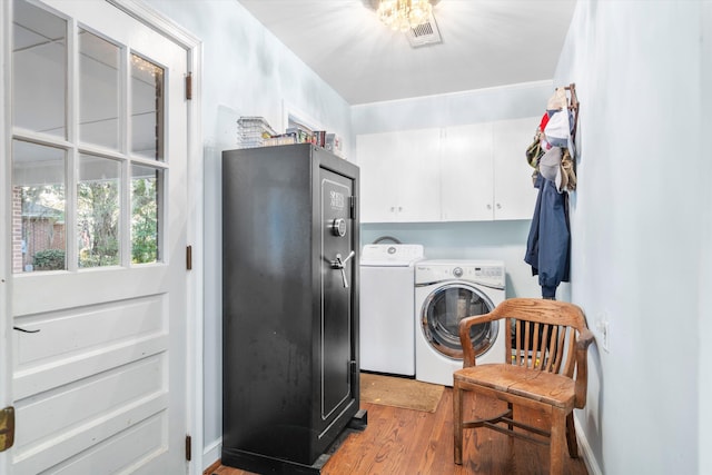 laundry area featuring visible vents, washer and dryer, cabinet space, and light wood-style floors