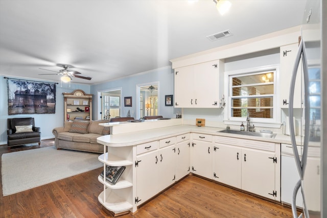 kitchen featuring visible vents, stainless steel refrigerator, light countertops, open shelves, and a sink