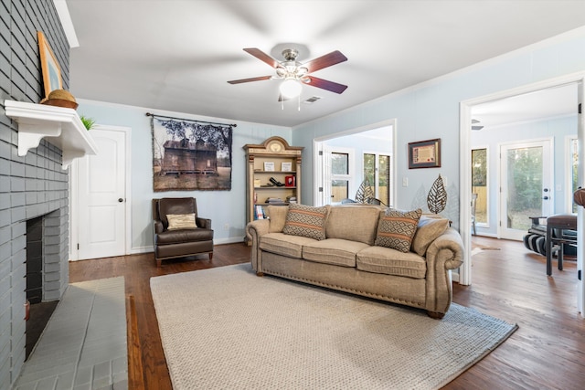 living area with dark wood-style flooring, a brick fireplace, visible vents, and crown molding