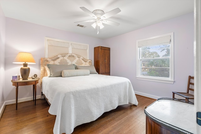 bedroom with baseboards, visible vents, ceiling fan, and wood finished floors