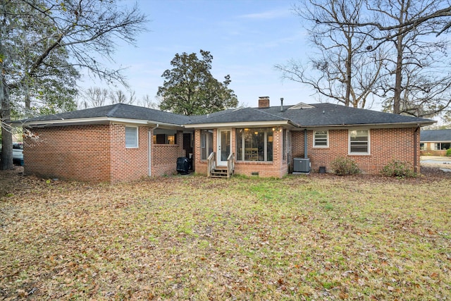 rear view of property featuring brick siding, a chimney, a lawn, crawl space, and central AC