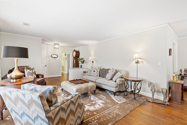 living area featuring ornamental molding, wood finished floors, visible vents, and baseboards