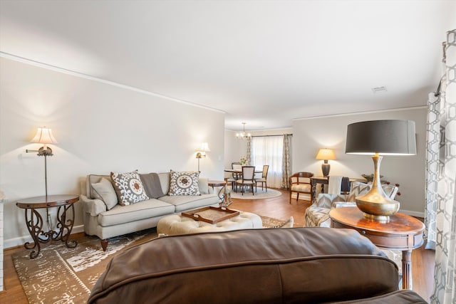 living room with baseboards, a chandelier, wood finished floors, and crown molding