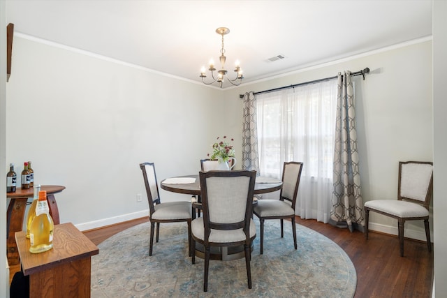 dining room with ornamental molding, wood finished floors, visible vents, and an inviting chandelier