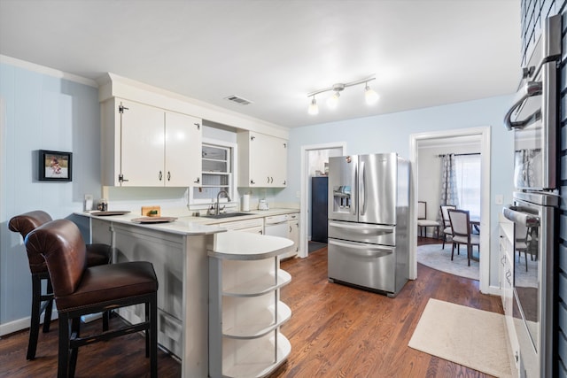 kitchen featuring dark wood-style floors, light countertops, appliances with stainless steel finishes, a sink, and a peninsula