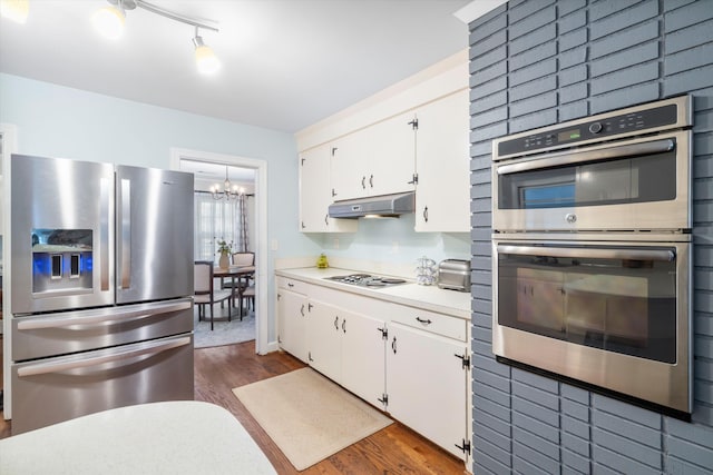 kitchen with dark wood-style floors, appliances with stainless steel finishes, light countertops, under cabinet range hood, and white cabinetry