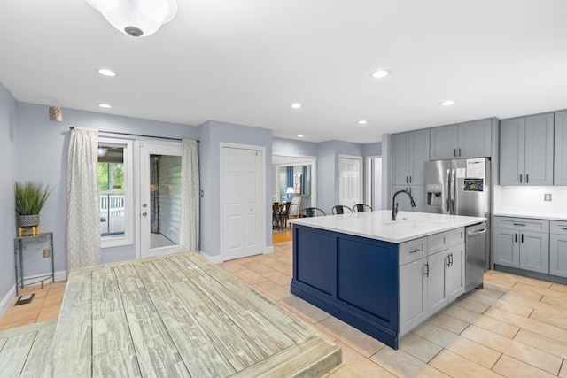 kitchen with a kitchen island with sink, gray cabinets, stainless steel appliances, sink, and light hardwood / wood-style floors