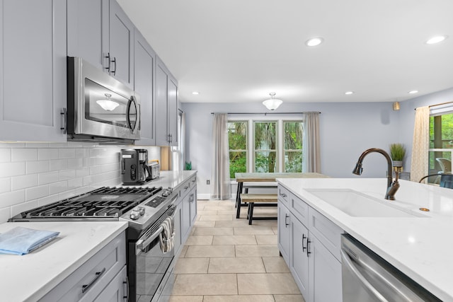 kitchen with backsplash, sink, gray cabinetry, appliances with stainless steel finishes, and light tile patterned flooring