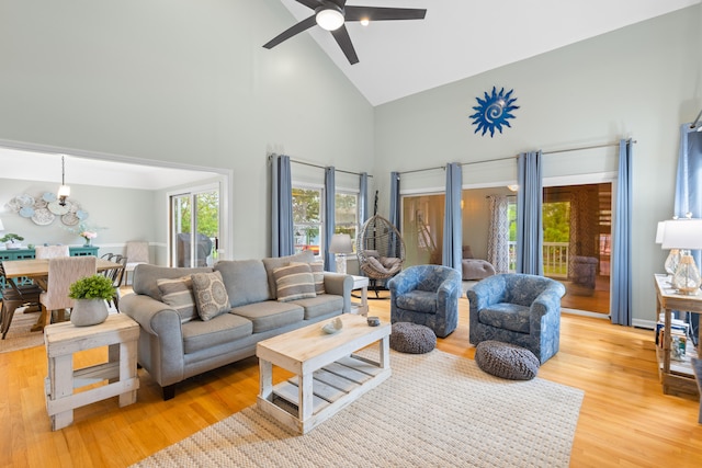 living room featuring ceiling fan with notable chandelier, high vaulted ceiling, and light hardwood / wood-style flooring