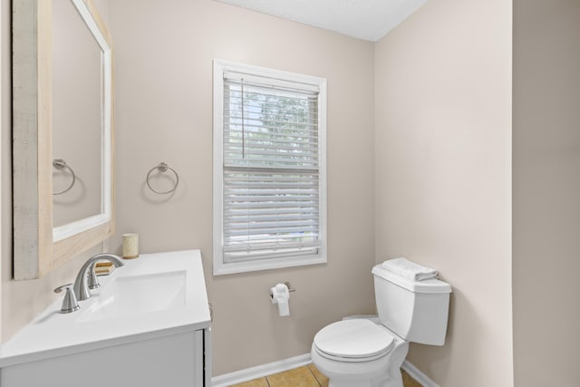 bathroom with vanity, toilet, a healthy amount of sunlight, and tile patterned floors