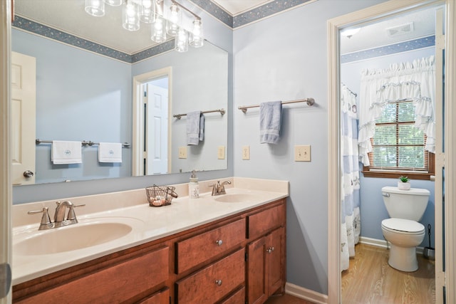 8661 Laurel Grove Ln, North Charleston, SC 29420 - bathroom featuring double vanity, toilet, a sink, and wood finished floors
