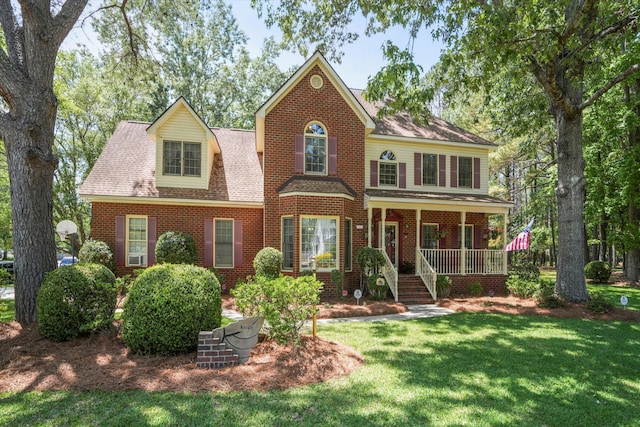 8661 Laurel Grove Ln, North Charleston, SC 29420 - view of front of property with covered porch, a shingled roof, a front lawn, and brick siding