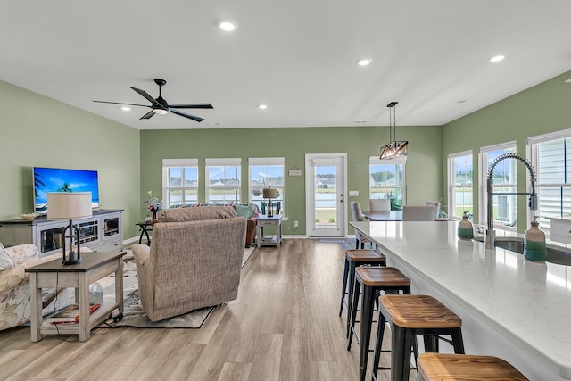 living area featuring healthy amount of natural light, light wood finished floors, recessed lighting, ceiling fan, and baseboards
