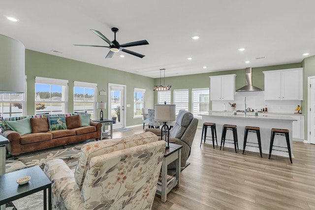 living area featuring recessed lighting, a ceiling fan, light wood finished floors, and baseboards