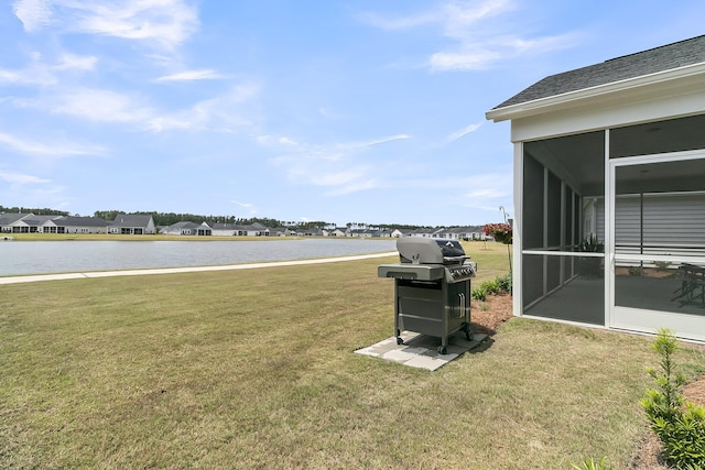 view of grassy yard with a sunroom, a water view, and a residential view