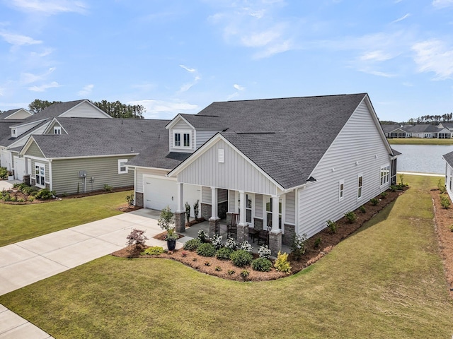view of front of house featuring covered porch, driveway, a shingled roof, a front yard, and a garage