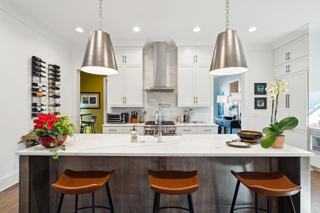 kitchen with a kitchen breakfast bar, a large island, dark hardwood / wood-style flooring, and wall chimney range hood