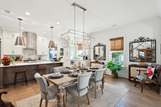 dining space featuring light wood-type flooring and crown molding