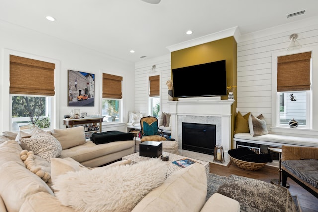 living room featuring hardwood / wood-style floors, ornamental molding, wooden walls, and a premium fireplace