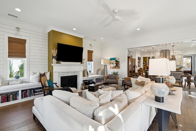 living room featuring hardwood / wood-style floors, ornamental molding, ceiling fan, and wooden walls