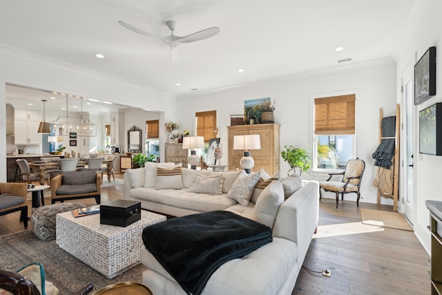 living room with light hardwood / wood-style floors, ceiling fan, and ornamental molding