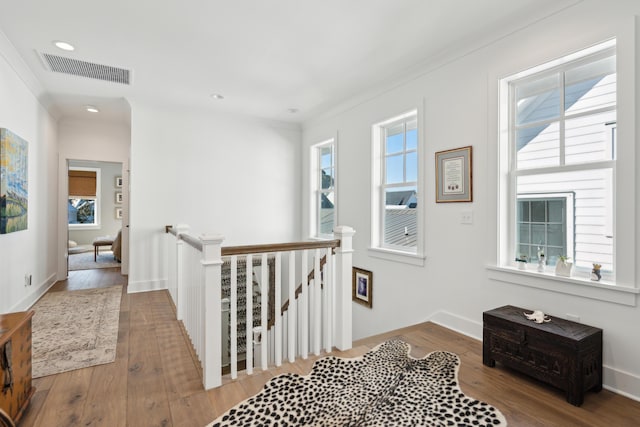 hall with hardwood / wood-style floors, ornamental molding, and a wealth of natural light