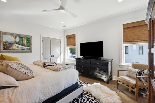 bedroom with ceiling fan, wood-type flooring, crown molding, and a closet