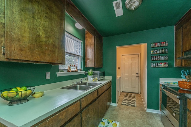 kitchen with stainless steel appliances, a sink, visible vents, baseboards, and light countertops