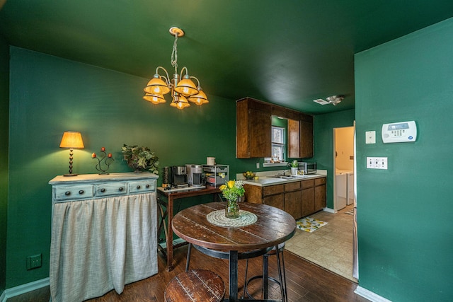 kitchen with a notable chandelier, light countertops, washing machine and dryer, wood finished floors, and baseboards