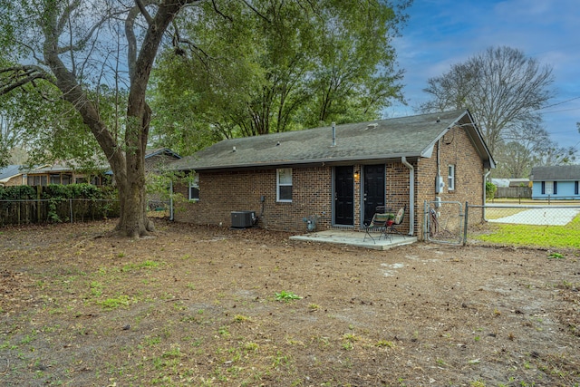 back of house featuring a shingled roof, a patio area, brick siding, and fence