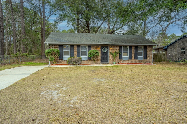 ranch-style house featuring brick siding, fence, a front lawn, and roof with shingles