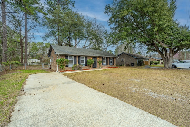 ranch-style home featuring brick siding, a front yard, and fence