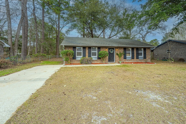 ranch-style house featuring a front lawn, roof with shingles, fence, and brick siding