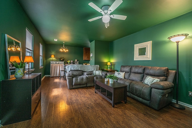 living area with ceiling fan with notable chandelier, wood finished floors, and baseboards