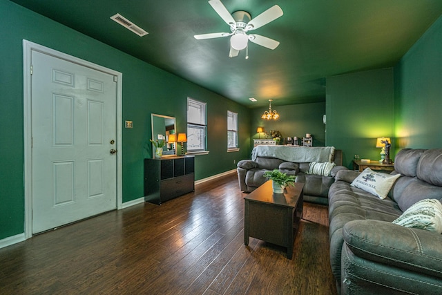 living area featuring ceiling fan with notable chandelier, visible vents, baseboards, and wood finished floors