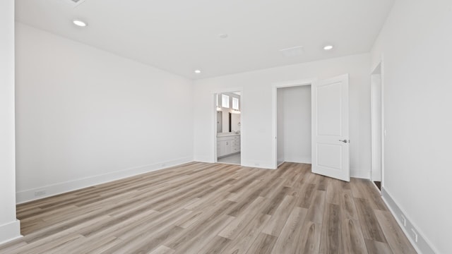 unfurnished bedroom with light wood-type flooring and connected bathroom