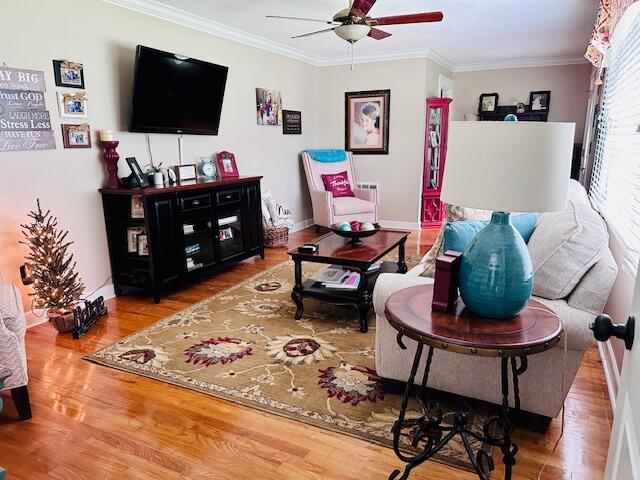 living room with crown molding, ceiling fan, and hardwood / wood-style flooring