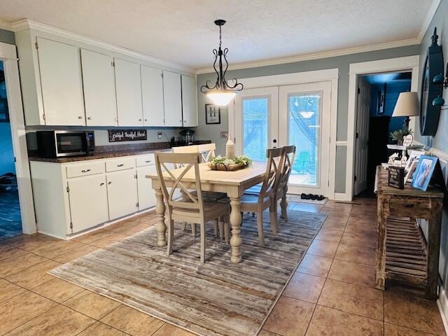 tiled dining room featuring ornamental molding, french doors, and a textured ceiling