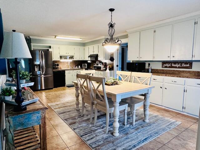 kitchen with appliances with stainless steel finishes, light tile patterned floors, white cabinets, and hanging light fixtures